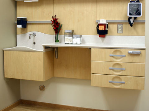 A clinic setup showing a splashless sink, cantilevering, and various cabinets. 