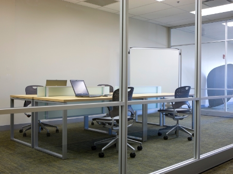 A clinical setting featuring a green Setu Stool and Compass System modular storage components with an integrated sink. 