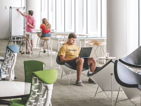 Students studying in an open lounge space within a library. 