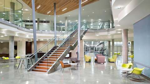 A large building lobby showcases a prominent staircase, with several lounge seating options.