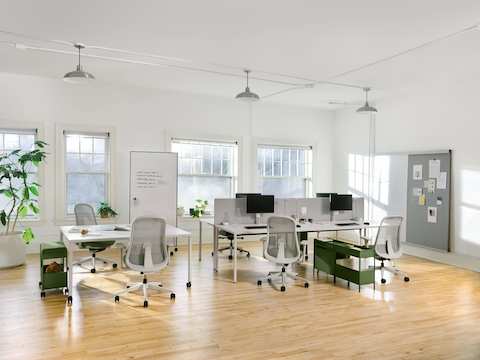 Four grey OE1 Rectangular Tables joined together to form a bench, with a grey OE1 Project Table, green OE1 Storage Trolleys and green Lino Chairs in the foreground and an OE1 Wall Rail and Board in the background.