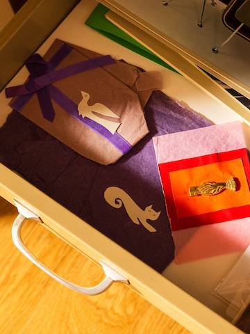 An overhead shot of an open drawer with colorful tissue paper and paper cut-outs.