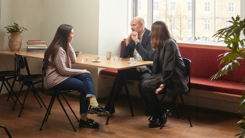 Amy Auscherman, Herman Miller’s Head of Archives and Brand Heritage, and HAY founders Rolf and Mette Hay sit on black chairs around a table at the Statens Museum for Kunst in Copenhagen. 