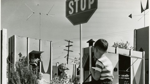 A vintage photo of children playing among large cartons. Select to go to an article about Ray and Charles Eames and their playful approach to design.