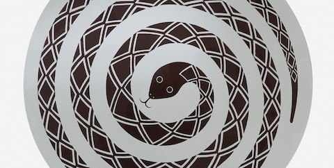 Overhead view of a round occasional table bearing the image of a coiled snake.